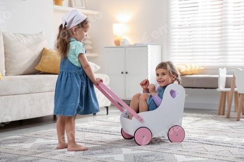 Preview: Cute little sisters playing with toy stroller at home