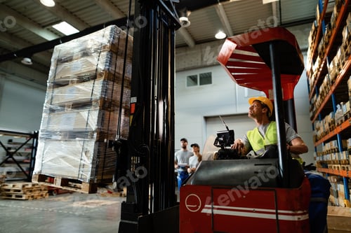 Preview: Warehouse worker moving pallets with a forklift in industrial building.