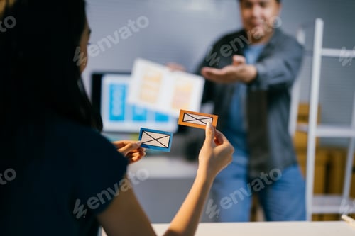 Preview: Businesswoman is holding two cards with drawings of envelopes, trying to decide which option is bett