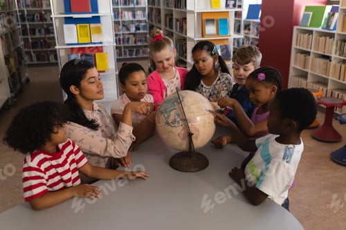 Preview: Female teacher teaching the kids about the globe at table in school library