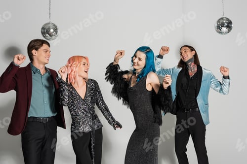 Preview: excited nonbinary friends in elegant clothes dancing at christmas party on grey background