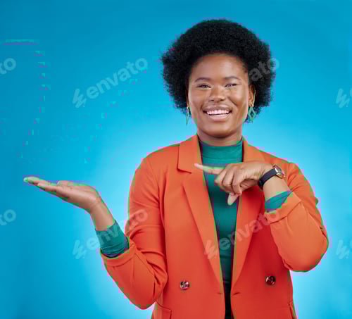 Preview: Happy black woman, portrait and pointing to palm for advertising against a blue studio background.
