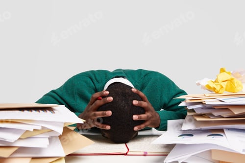 Preview: People, work, deadline and stress concept. Overworked dark skinned manager leans on table, keeps bot