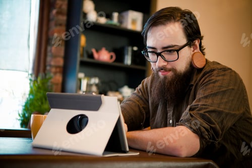 Preview: Young man having coffee and using digital tablet in cafe