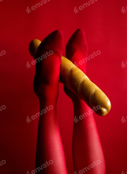 Preview: Beautiful Female Legs In Red Tights Hold A Baguette With Their Feet Up Photo