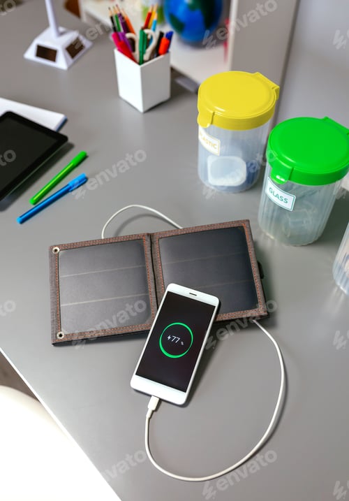 Preview: Mobile phone charging with portable solar panel and selective trash bins over desk in classroom