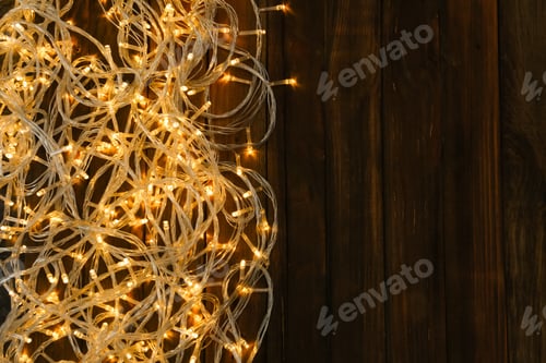Preview: Glowing Christmas lights on wooden background, top view. Space for text
