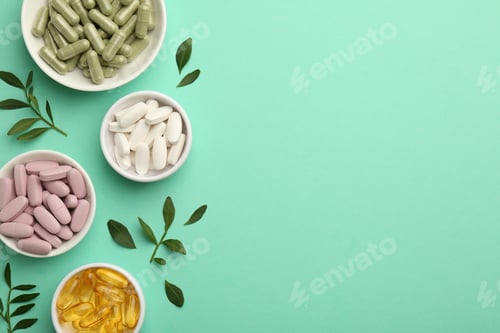 Preview: Different vitamin capsules in bowls and leaves on turquoise background, flat lay. Space for text