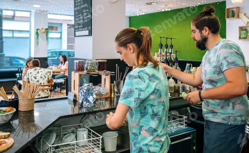 Preview: Two young baristas washing dishes in a modern cafeteria