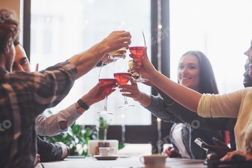 Preview: Group of young friends having fun and laughing while dining at table in restaurant