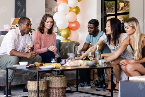 Preview: Friends enjoying snacks and drinks at home during festive celebration