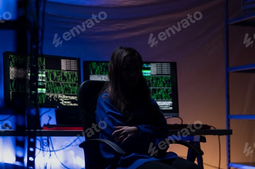 Preview: Anonymous hacker woman by computer in the dark room at night, cyberwar concept.