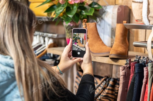 Preview: Woman taking a photo of some shoes in a clothing store
