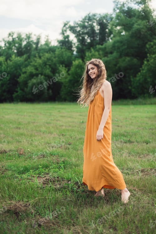 Preview: A beautiful smiling girl with flowing hair walks through a meadow