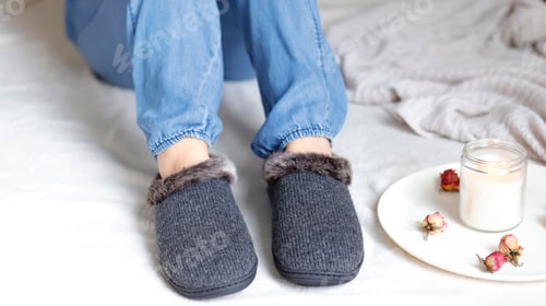 Preview: Woman sitting on the bed , wearing jeans and a cozy slippers