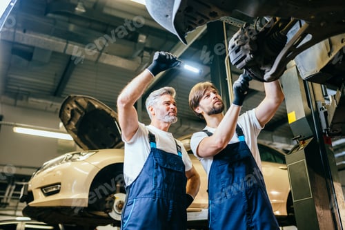 Preview: Two handsome professional car mechanic are Investigating a Vehicle on a lift