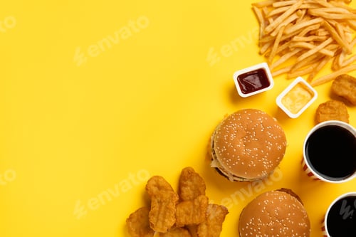 Preview: Different fast food on yellow background, flat lay. Space for text