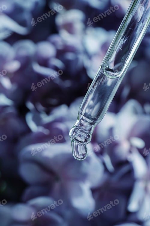 Vista previa: Una gota de aceite cosmético cae de la pipeta sobre un fondo floral morado.