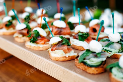 Preview: Row of salmon snack sandwiches with cheese and vegetables. Vegetarian healthy food. Catering table