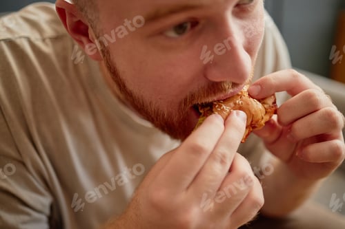 Preview: Young Adult Man Eating Sandwich Indoors during Mealtime