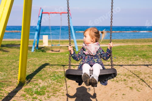 Preview: Happy child girl on swing in summer day