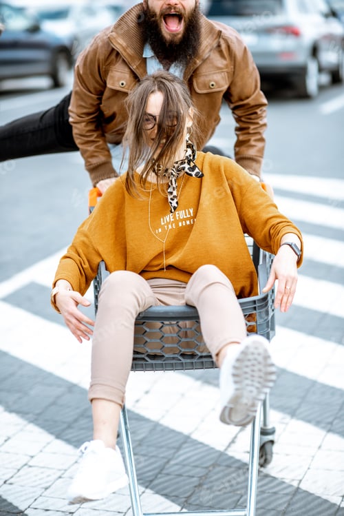 Preview: Couple riding with shopping cart on the parking outdoors