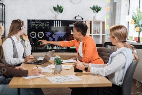 Preview: Group of diverse female colleagues looking at computer monitor with worldwide business concept