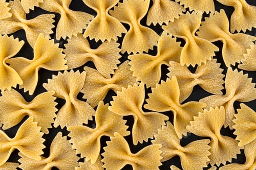Preview: Farfalle pasta pattern on black background, top view, flat lay texture
