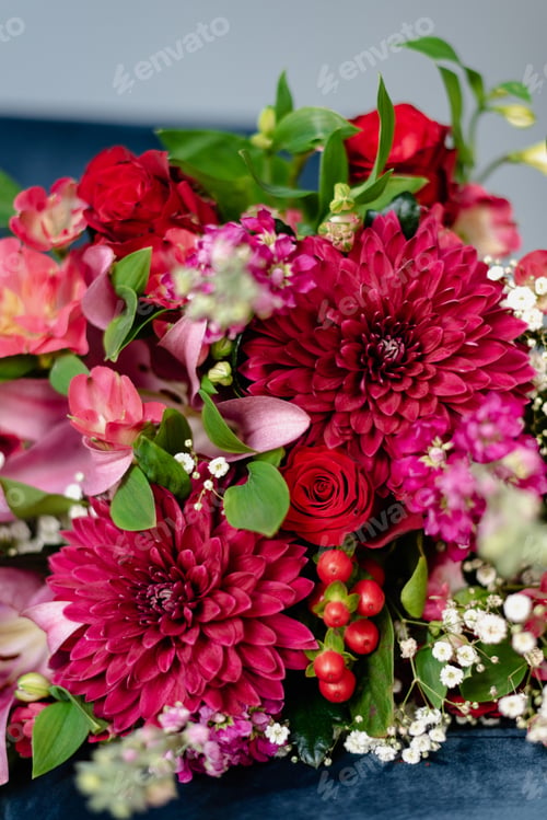 Preview: Bunch of flowers in burgundy tones on a dark blue velvet chair.