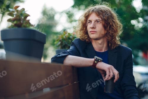 Preview: Red haired hipster man sitting on bench thinking