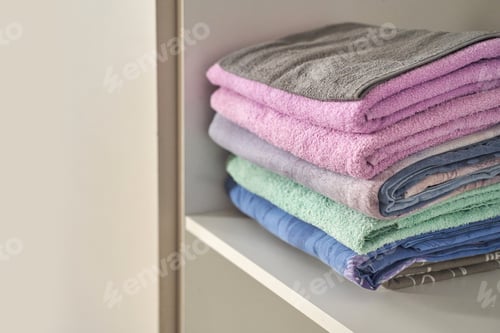 Preview: Neatly stacked multicolored towels on shelf for bathroom organization and decoration