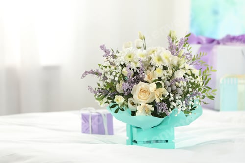 Preview: Beautiful bouquet of flowers in decorative crate on bed. Space for text