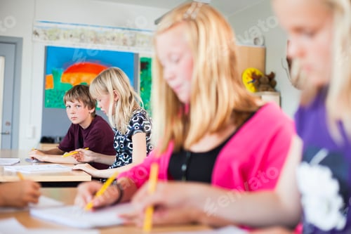 Preview: Portrait of serious schoolboy sitting at desk in classroom