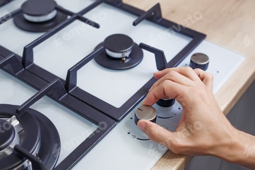 Preview: Close up of man's hand set temperature on control panel of hob