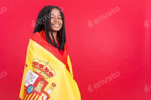 Preview: Happy african woman wrapped by a spanish national flag