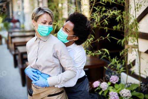 Preview: Happy waitress with protective face masks having fun while working at outdoor cafe.
