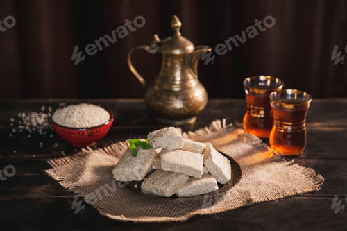 Preview: Pieces of tahini halva, sesame seeds in a bowl, tea in Turkish armudas, an vintage jug.