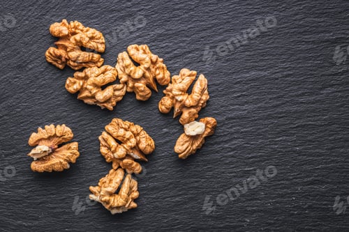 Preview: Peeled dried walnut kernels on black table. Top view.