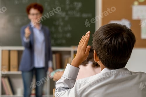 Preview: Contemporary schoolboy with raised hand going to answer question of teacher