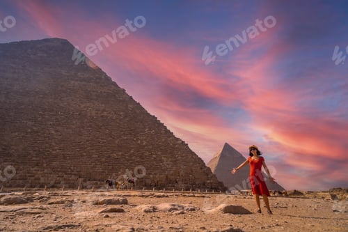 Preview: A young girl in a red dress at the pyramid of Cheops the largest pyramid