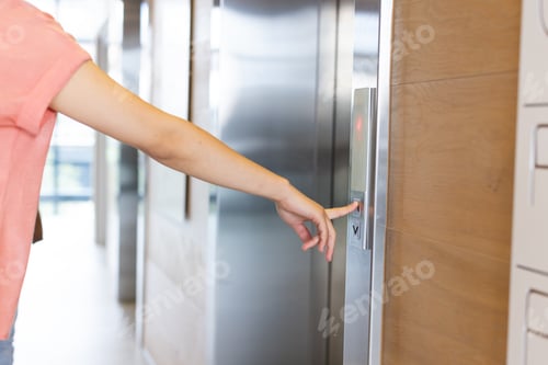 Preview: A young Asian female is pressing elevator button in a modern business office
