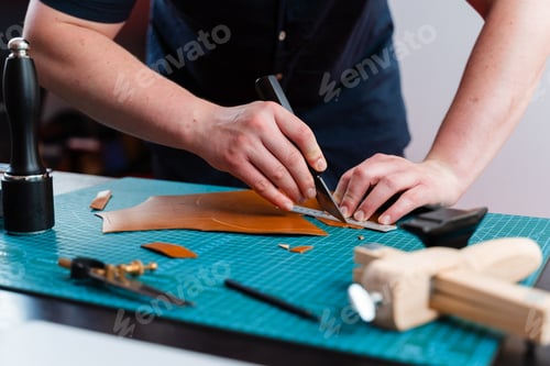 Preview: Cutting and preparing leather by artisan. Knife and ruler used for shaping pieces