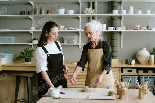 Preview: Senior Woman Explaining Pottery Techniques to Young Adult Woman