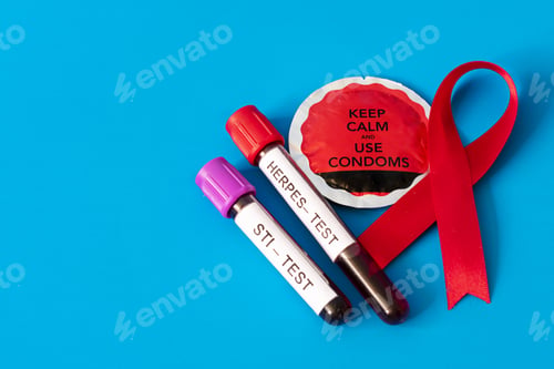 Preview: AIDS ribbon with blood tubes from sexually transmitted disease tests and condom on blue background