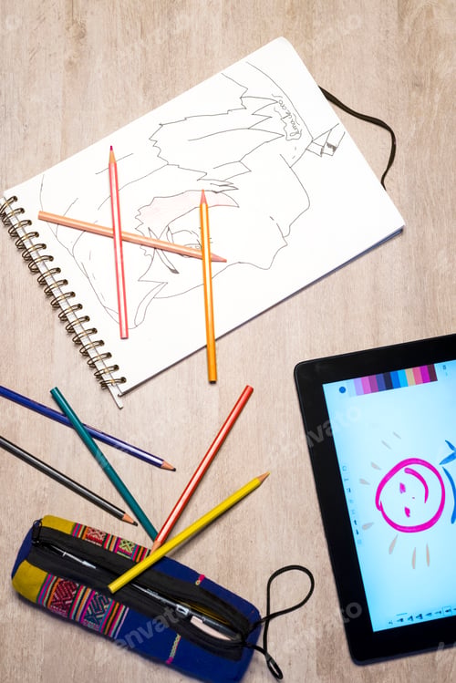 Preview: Above view of open exercise book, pencil crayons and tablet on white desk