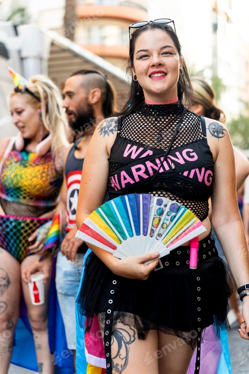 Preview: Woman holding rainbow fan celebrating at gay pride parade