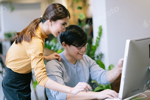 Preview: Young Asian businesswoman looking at computer monitor discussing marketing online results project.