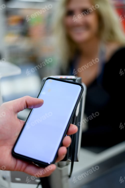 Preview: Mans hand making a contactless payment with his smartphone at a supermarket