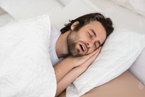 Preview: Tired young caucasian male with open mouth sleeping on white soft bed in bedroom in spare time