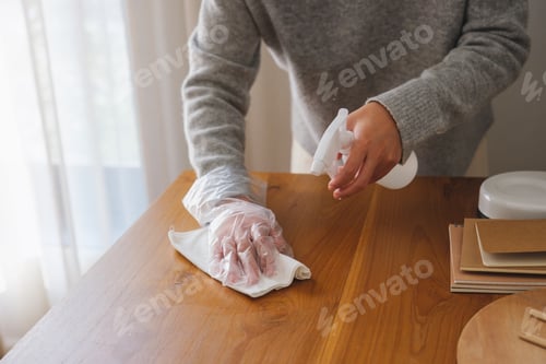Preview: Closeup image of a woman wearing protective glove, cleaning and washing wooden table at home